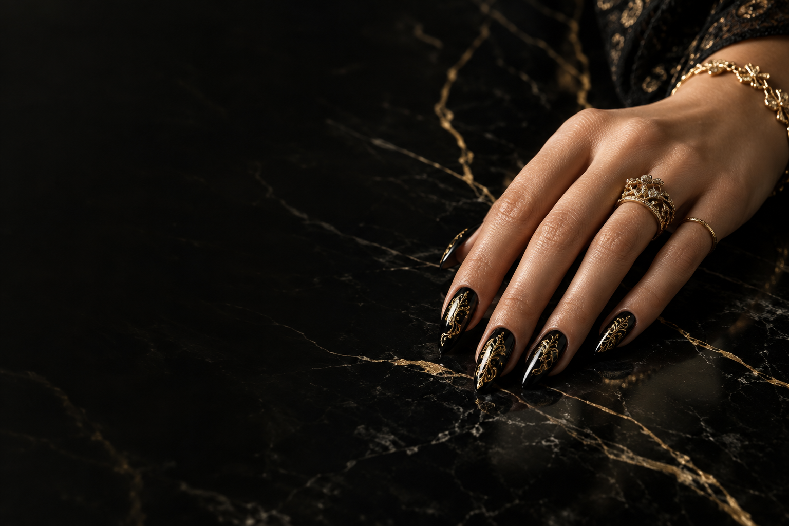 Sculptural black and gold lace manicure resting on black marble