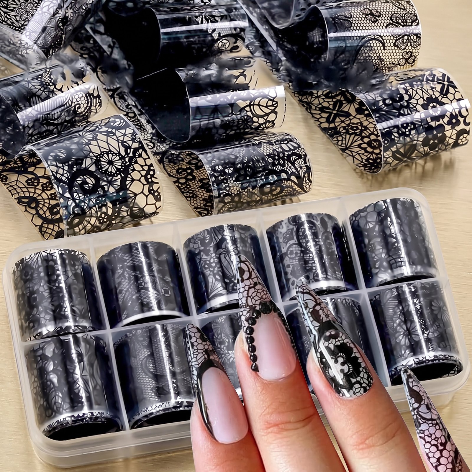 Black lace foil rolls, storage tray and nude manicure with lace details, on a gold background